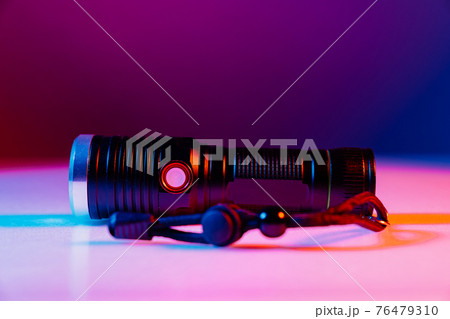 A small black flashlight in colored lighting. A small black flashlight in colored lighting. 76479310