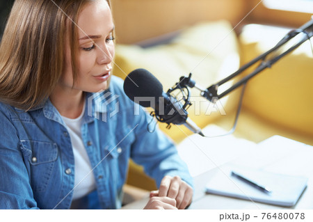 Young woman telling facts or news in microphone on radio. Young woman telling facts or news in microphone on radio. 76480078