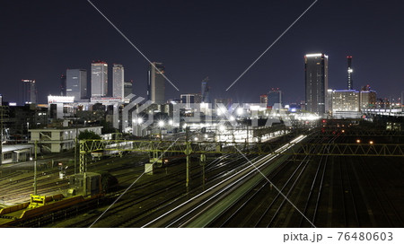 名古屋市の黄金跨線橋から見たJRとあおなみ線の線路、電車の光跡、名古屋駅周辺の高層ビル群の夜景 76480603