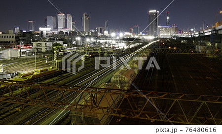 名古屋市の黄金跨線橋から見たJRとあおなみ線の線路、電車の光跡、貨物列車、高層ビル群の夜景 76480616