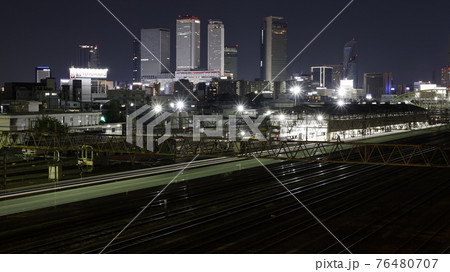 名古屋市の黄金跨線橋から見たJRとあおなみ線の線路、電車の光跡、名古屋駅周辺の高層ビル群の夜景 76480707