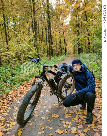 Sporty man on an electric bike in the woods. A pleasant sports hobby. Ecological transport. Sporty man on an electric bike in the woods. A pleasant sports hobby. Ecological transport. 76481935