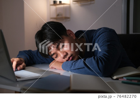 Sleepy exhausted collage young man working overtime. 76482270