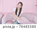 Happy woman smile and sitting on pink sofa at home 76483380