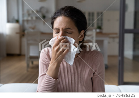 Ill latina lady catching cold blow nose in paper tissue Ill latina lady catching cold blow nose in paper tissue 76486225