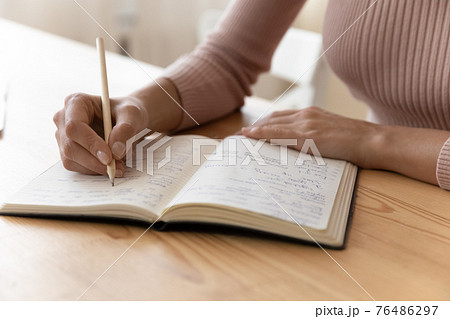 Young woman hand hold pencil take notes to paper daybook 76486297