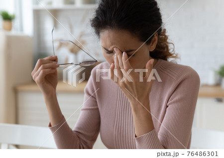 Sad millennial latina female take off spectacles massage nasal bridge Sad millennial latina female take off spectacles massage nasal bridge 76486301