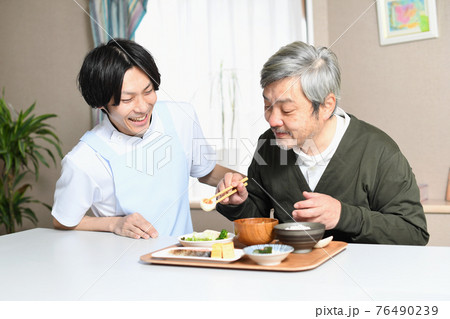 食事をする高齢者男性とエプロン姿の男性介護士 食事をする高齢者男性とエプロン姿の男性介護士 76490239