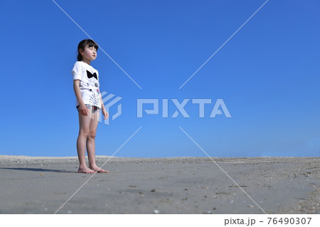 裸足の少女が砂場に立っている風景 76490307