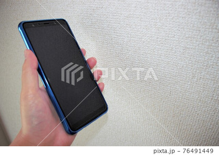手に持つスマホ 76491449
