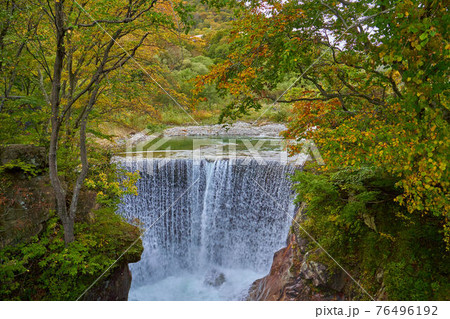 群馬県みなかみ町の紅葉に包まれる土合橋バス停前の湯吹きの滝の写真素材