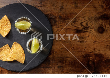 Tequila with lime slices and nacho chips, shot from the top Tequila with lime slices and nacho chips, shot from the top 76497116