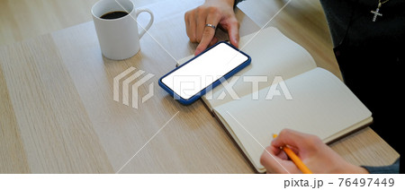Cropped shot of man writing on empty notebook and using smart phone at home office. Cropped shot of man writing on empty notebook and using smart phone at home office. 76497449