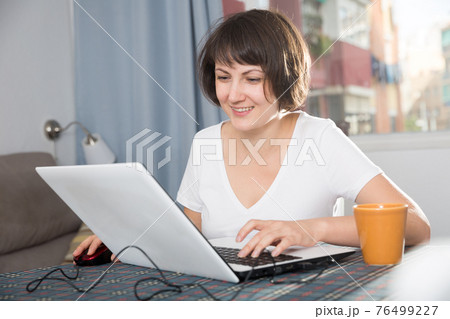 Woman surfing in Internet using laptop Woman surfing in Internet using laptop 76499227