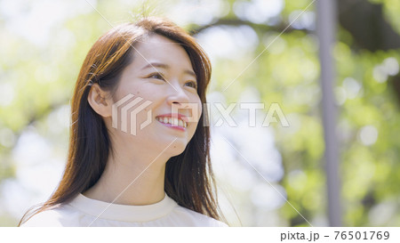 屋外で見上げる若い女性 76501769