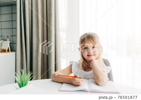 Smiling girl writes in notebook. Education concept. Home schooling. Homework. 76501877