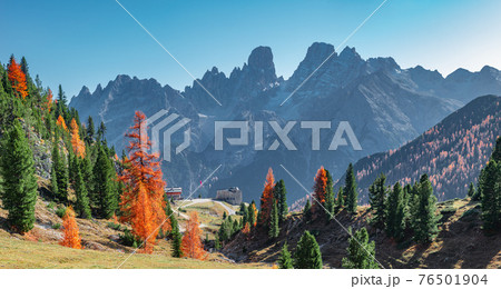 Panoramic view of magical Dolomite peaks at the national park Three Peaks (Tre Cime, Drei Zinnen) and mountain hut in Autumn colors during sunset backlit at blue sky, South Tyrol, Italy, golden season 76501904