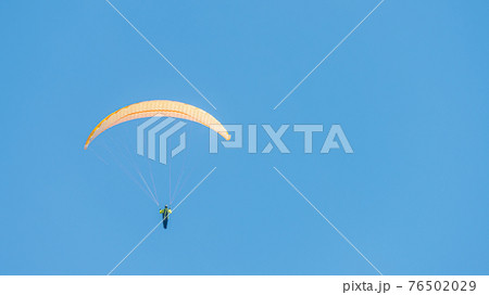 Beautiful paraglider flying in blue sky with copy space for text and smooth background, wide angle Beautiful paraglider flying in blue sky with copy space for text and smooth background, wide angle 76502029