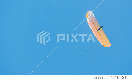 Beautiful paraglider flying in blue sky with copy space for text and smooth background, wide angle Beautiful paraglider flying in blue sky with copy space for text and smooth background, wide angle 76502030