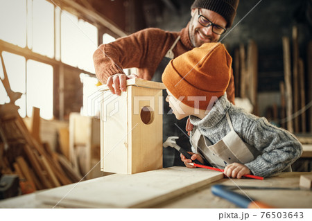 Dad and kid assembling wooden bird house 76503643