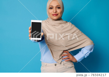 Soft focus on mobile phone in Arab Muslim woman's hands Soft focus on mobile phone in Arab Muslim woman's hands 76504217