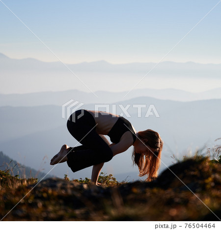 Fit young woman doing yoga exercise in mountains. 76504464