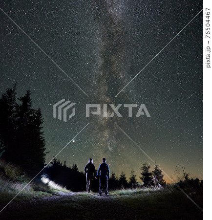 Loving couple holding hands under night starry sky. 76504467