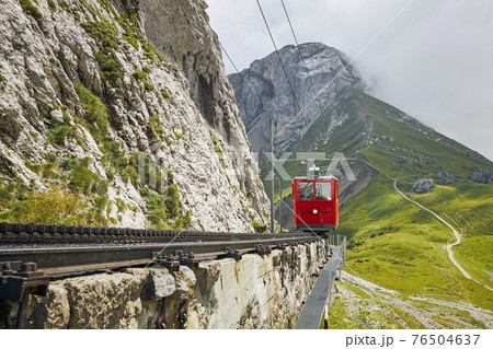 Cogwheel train passing mountain landscape of Swiss Alps 76504637