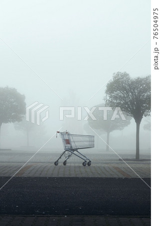Abandoned shopping cart on parking lot in thick fog 76504975