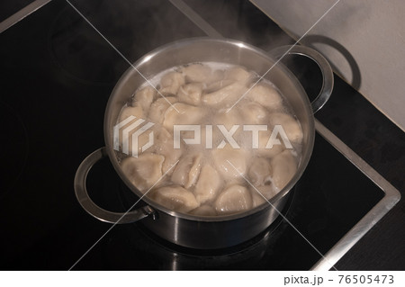 Cooking dumplings with meat by boiling in water in a pan, details, closeup Cooking dumplings with meat by boiling in water in a pan, details, closeup 76505473