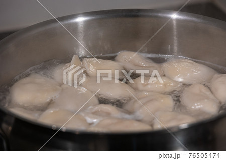 Cooking dumplings with meat by boiling in water in a pan, details, closeup Cooking dumplings with meat by boiling in water in a pan, details, closeup 76505474