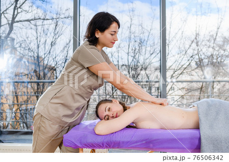 Masseur woman massage relaxed girl back indoors Masseur woman massage relaxed girl back indoors 76506342