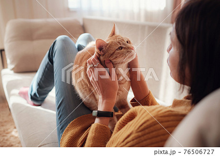 Young woman resting with pet in sofa at home. 76506727