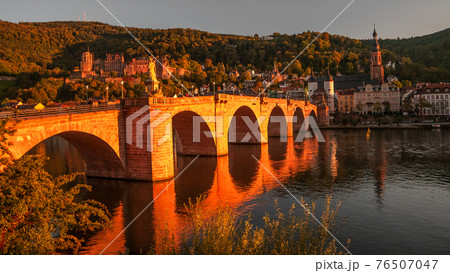 Panoramic view during red sunset at old bridge, downtown and castle in Heidelberg, Germany Panoramic view during red sunset at old bridge, downtown and castle in Heidelberg, Germany 76507047