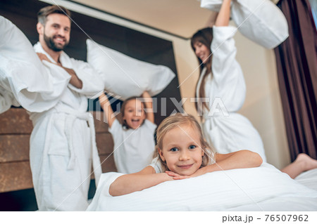 Family in white robes having a pillow fight 76507962