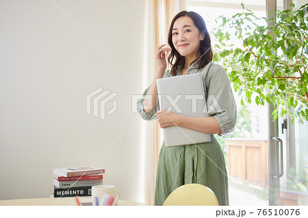 リビングでパソコンを持って立っている女性 76510076