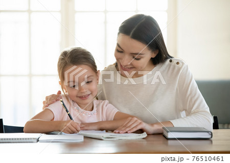 Happy young mom and little daughter do homework Happy young mom and little daughter do homework 76510461
