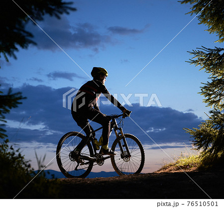 Male cyclist sitting on bicycle under beautiful night sky. Male cyclist sitting on bicycle under beautiful night sky. 76510501