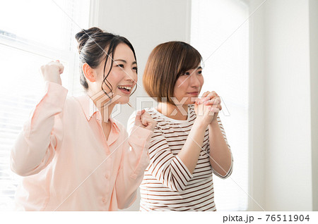 テレビでスポーツのオンライン観戦する二人の女性 76511904