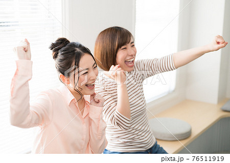 テレビでスポーツのオンライン観戦する二人の女性 76511919