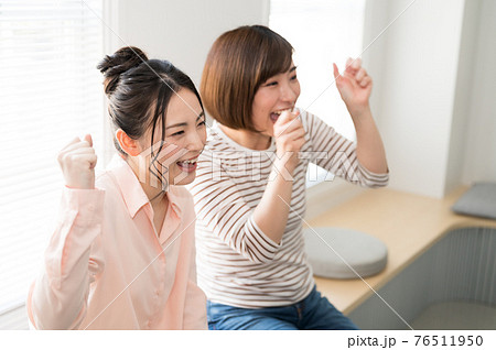 テレビでスポーツのオンライン観戦する二人の女性 76511950