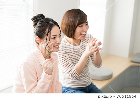 テレビでスポーツのオンライン観戦する二人の女性 テレビでスポーツのオンライン観戦する二人の女性 76511954