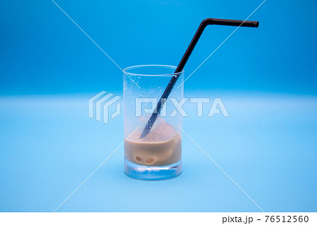 飲みかけのカフェオレ 青い背景とストローの刺さったグラスの写真素材 
