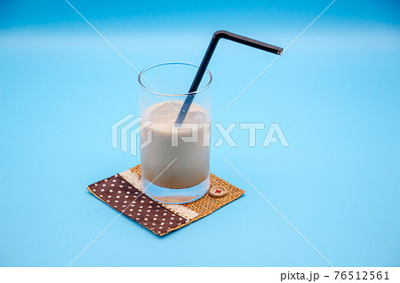 飲みかけのカフェオレ 青い背景とストローの刺さったグラスの写真素材 