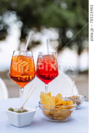 Two refreshing Italian cocktails with snacks on the table (Vertical photo) 76513462