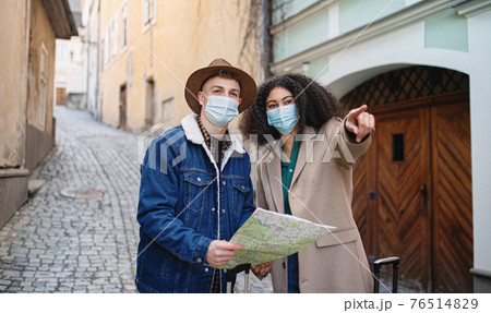 Young couple tourists with map on holiday in old town, coronavirus concept. 76514829