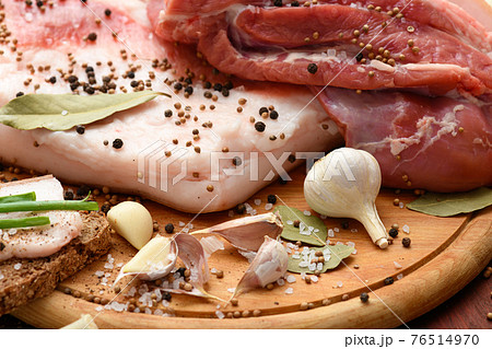 raw pork meat and lard with salt, spices and garlic on a cutting board, dark wooden background raw pork meat and lard with salt, spices and garlic on a cutting board, dark wooden background 76514970