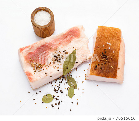 raw lard two pieces and salt, spices and bay leaf on white background, pork fat 76515016