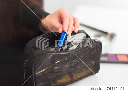 female hand pulls out a blue tube of black cosmetic bag 76515101