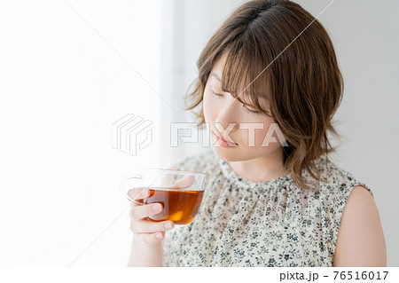 窓辺で紅茶のカップを持つ若い女性 窓辺で紅茶のカップを持つ若い女性 76516017